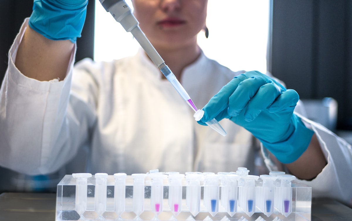 Female scientist pipetting colored chemicals into laboratory tubes