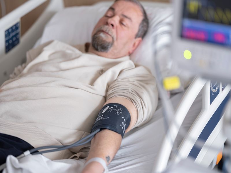 Elderly patient recovering in hospital bed after cardiac procedure